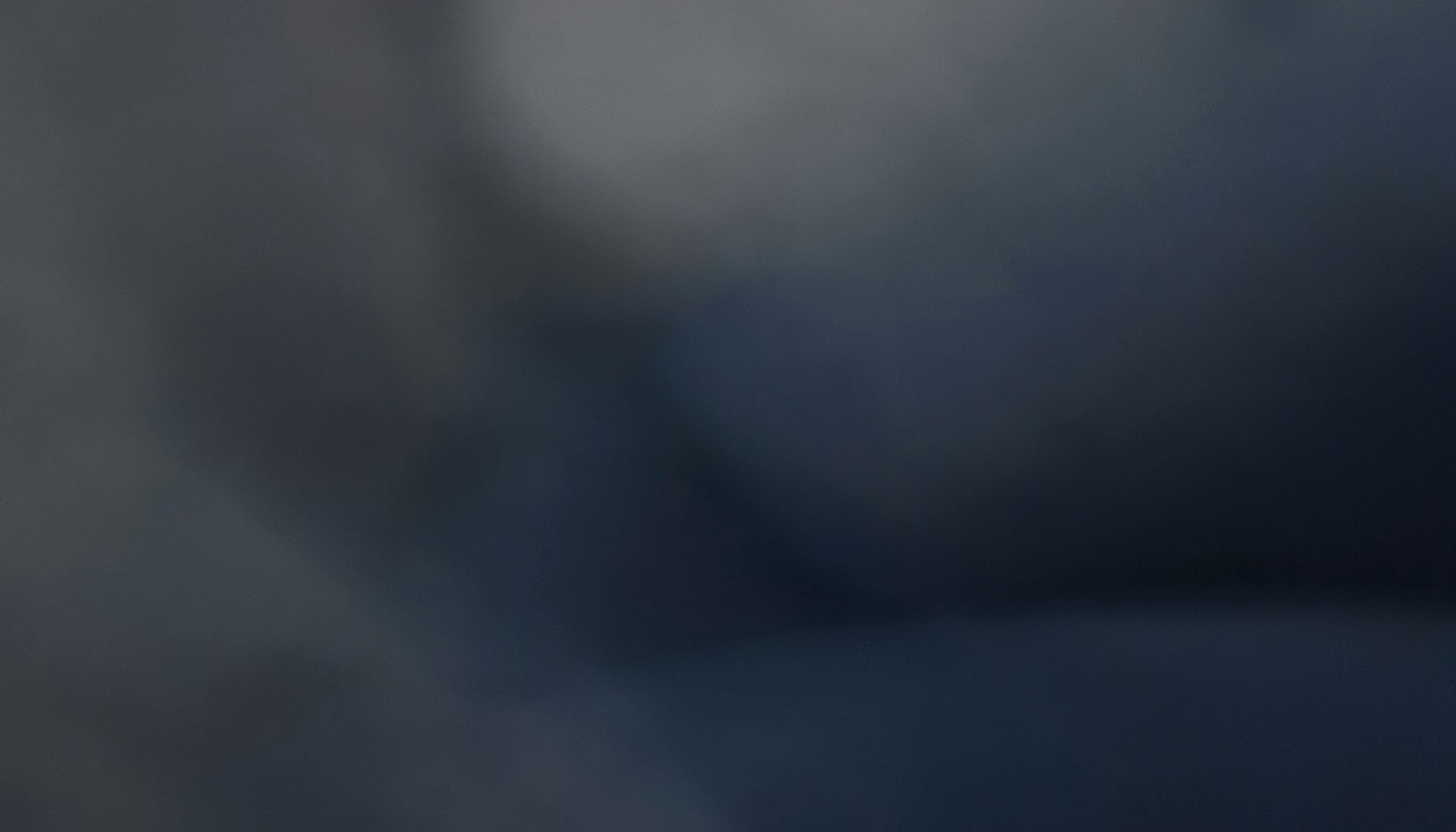 Abstract horizontal composition in muted charcoal and deep indigo, evoking a quiet studio atmosphere
