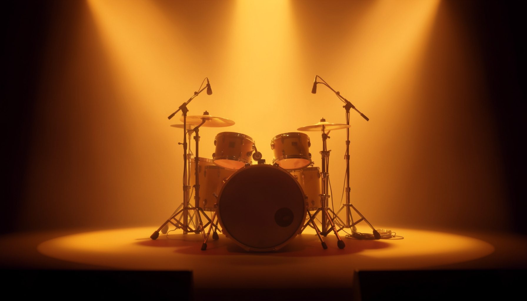 Concert stage bathed in warm amber light with drum kit center-frame