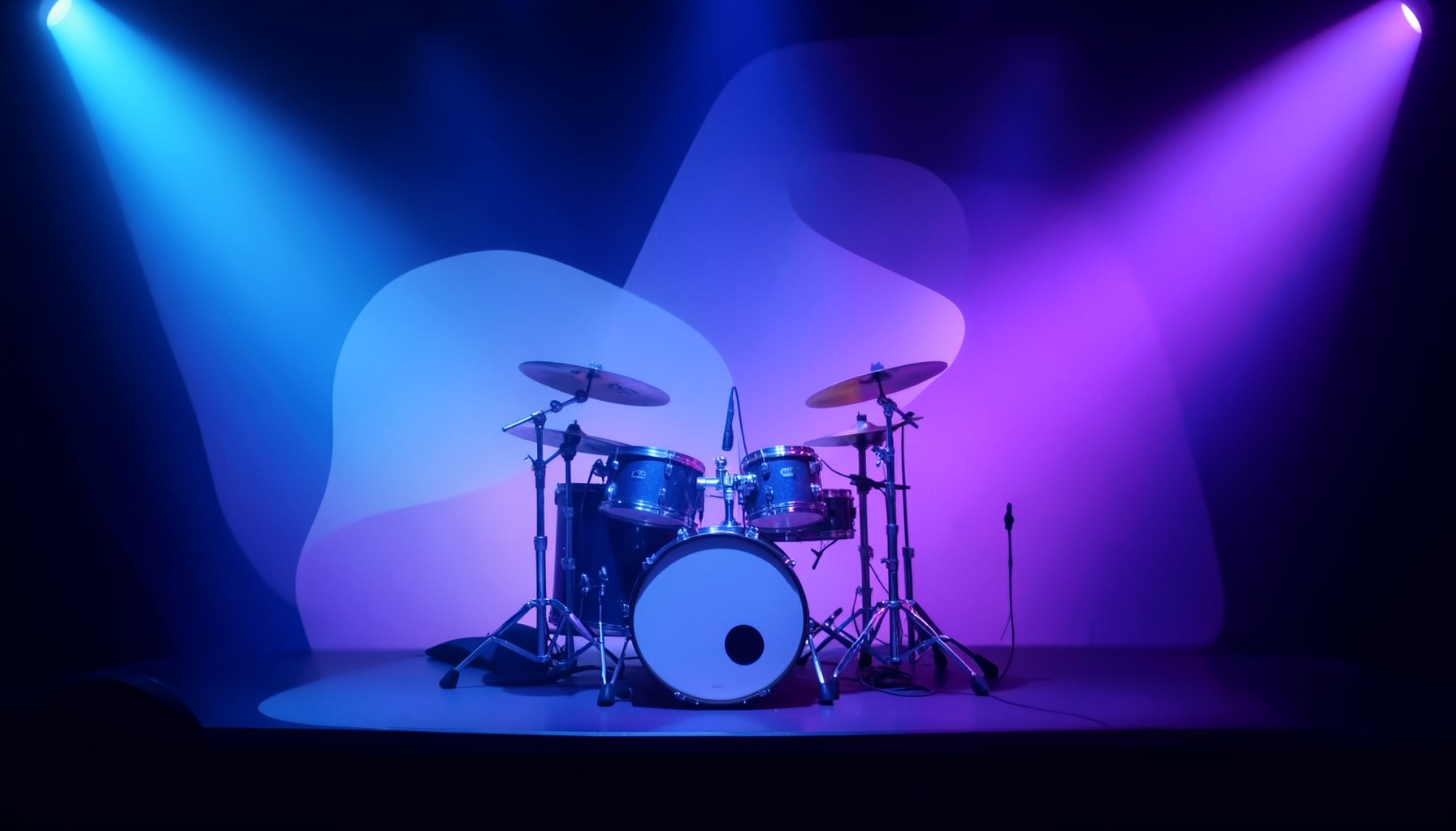 A concert stage bathed in blue and purple light with a drum kit at center, capturing the energy of a live show